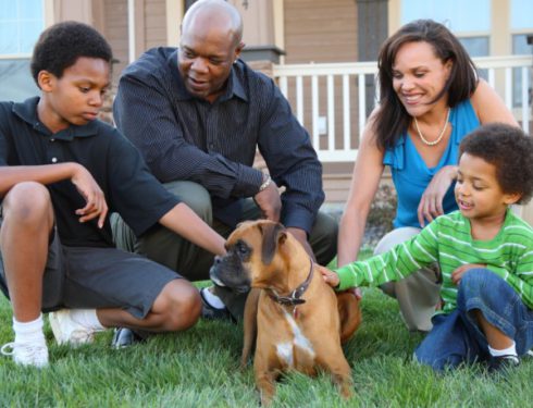 Family of four with dog outside home